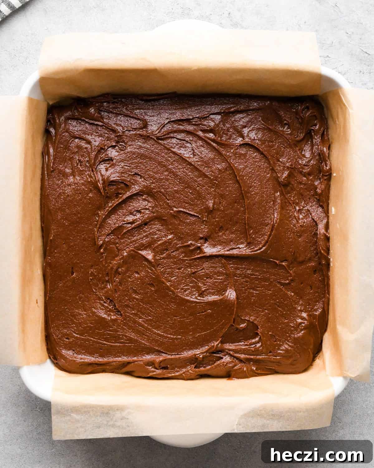 cookie dough brownie batter spread into the parchment lined baking dish before baking