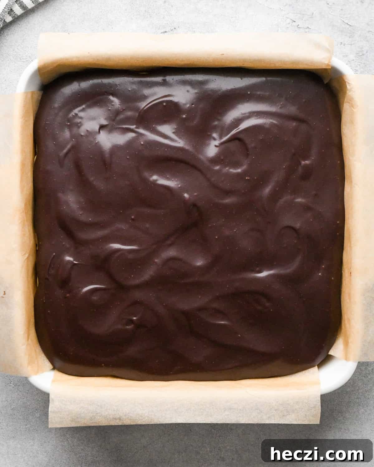 chilled cookie dough brownies in a white ceramic square baking dish lined with parchment paper