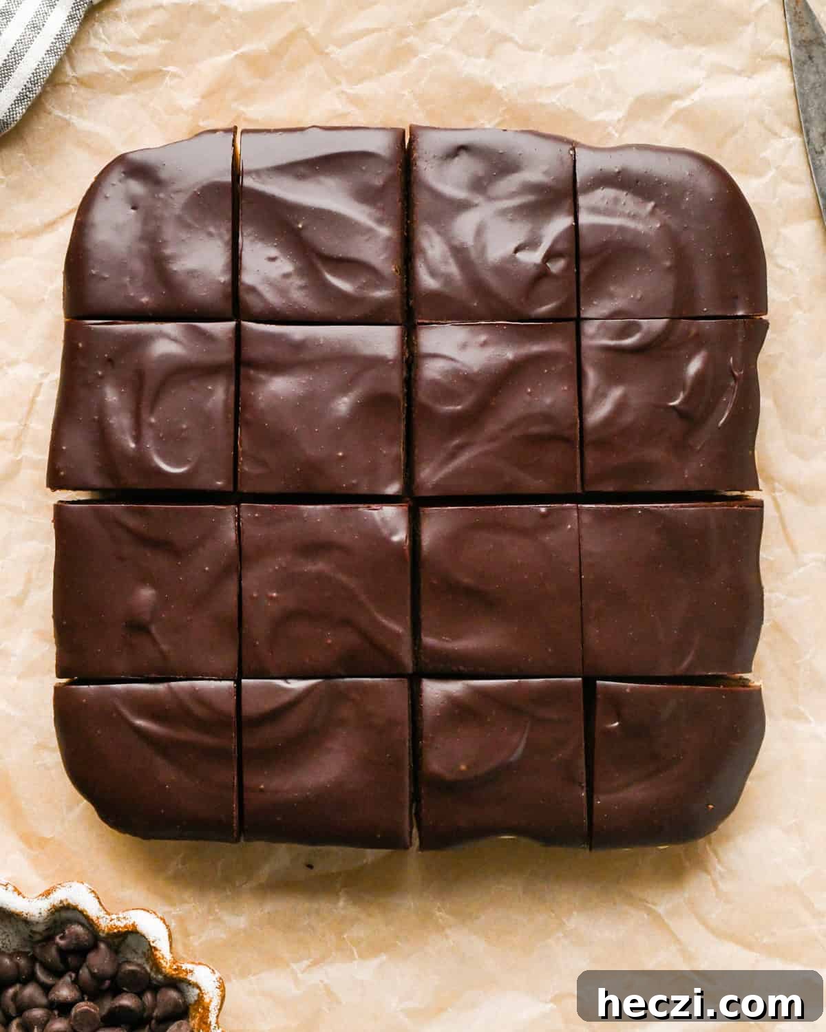 chilled cookie dough brownies on parchment paper cut into 16 squares. 