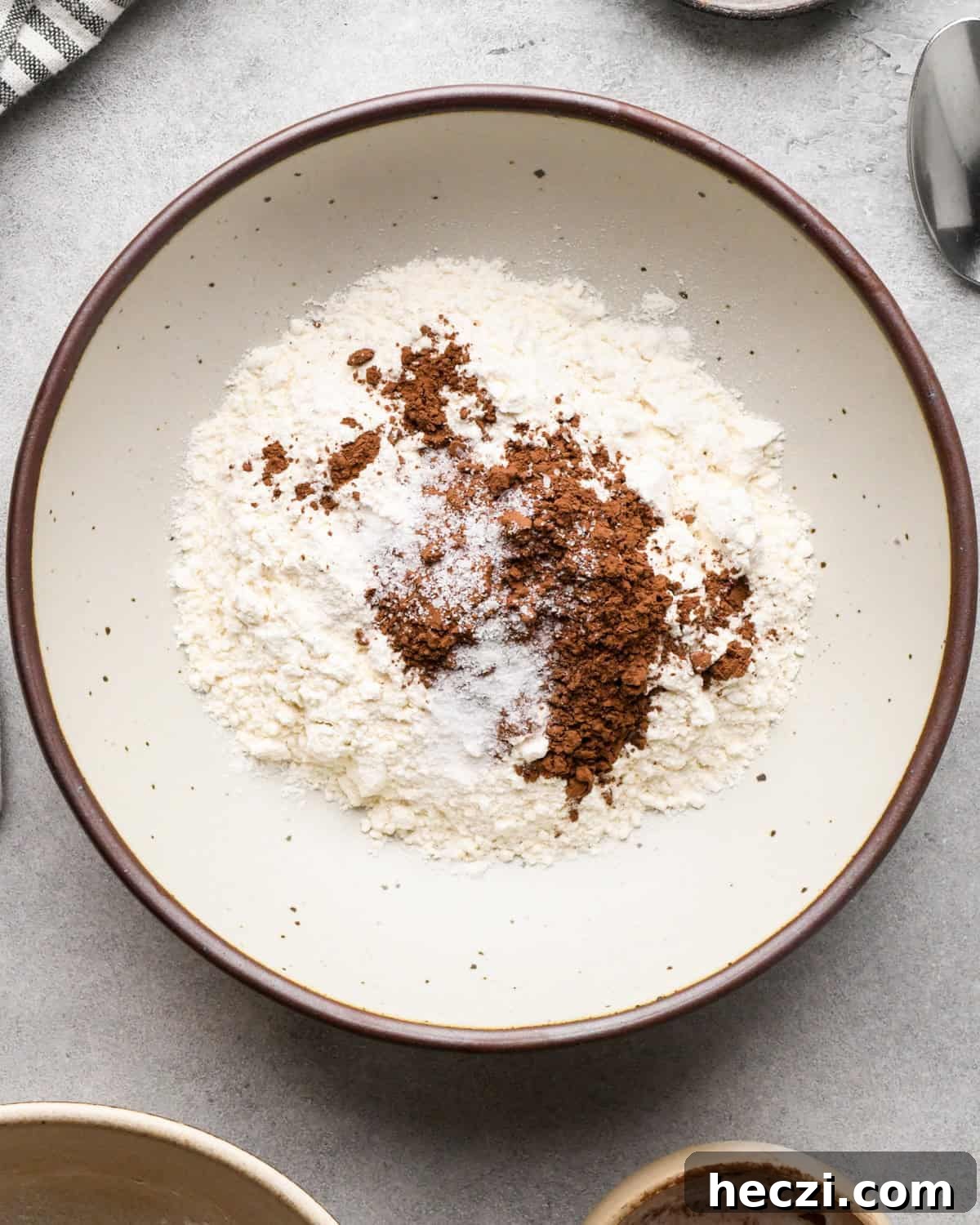 making cookie dough brownies - flour, cocoa powder and salt in a white ceramic bowl with a brown rim before mixing