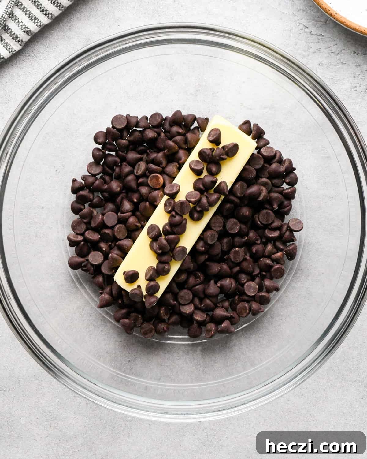 making cookie dough brownies - a stick of butter and chocolate chips in a glass bowl 