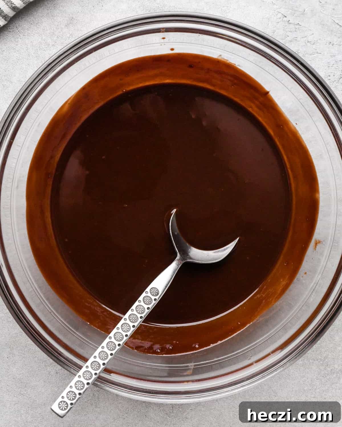 making cookie dough brownies - melted chocolate and butter in a glass bowl with a metals spoon