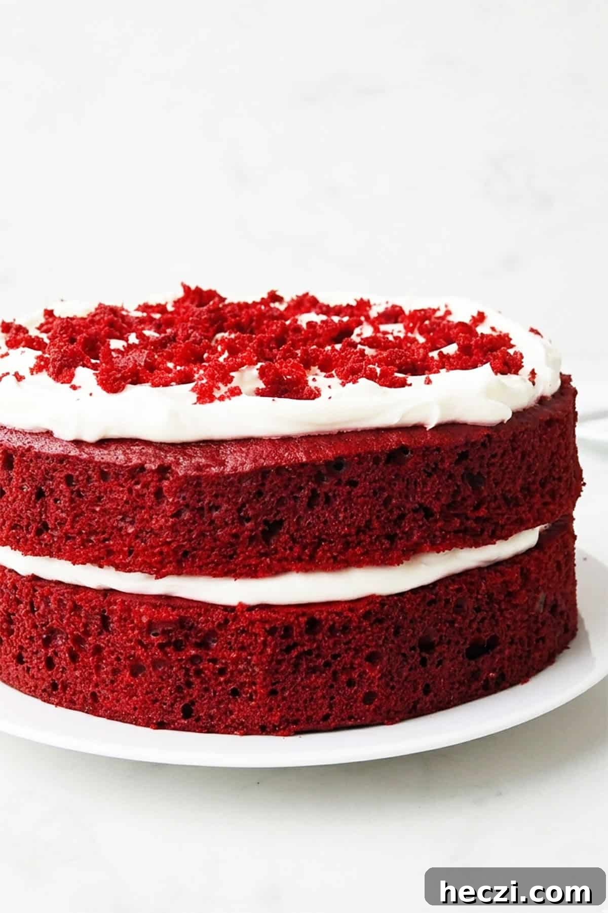 Moist Red Velvet Layer Cake Recipe for Perfect Celebrations 4 Closeup shot of layer cake on white serving dish.