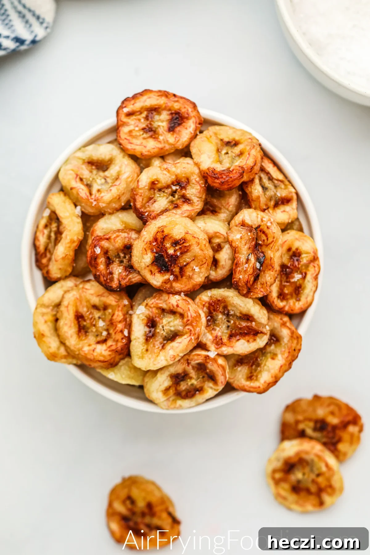 Crispy Air Fryer Banana Chips Recipe — Quick Snack at Home 2 Air fried banana chips in a bowl with salt sprinkled on them, ready to serve.