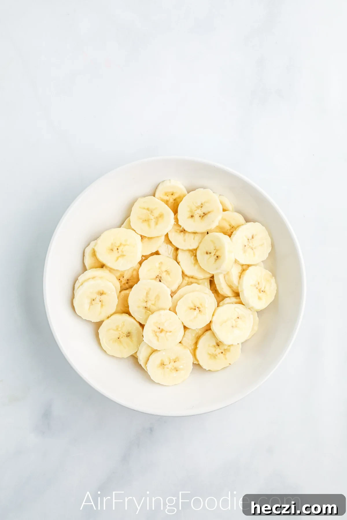 Crispy Air Fryer Banana Chips Recipe — Quick Snack at Home 5 Banana chips in a bowl, tossed with oil before placing into the air fryer.
