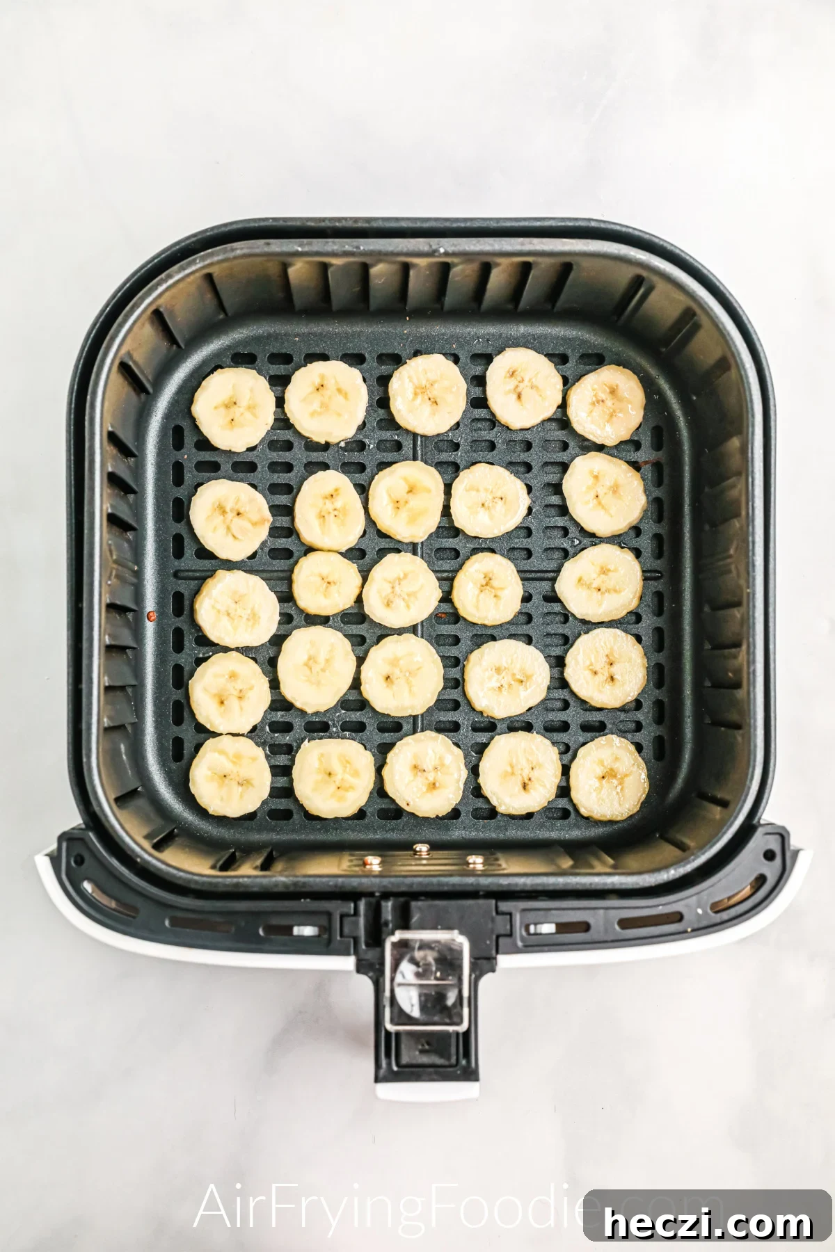Crispy Air Fryer Banana Chips Recipe — Quick Snack at Home 6 Banana slices in a single layer in the basket of the air fryer.