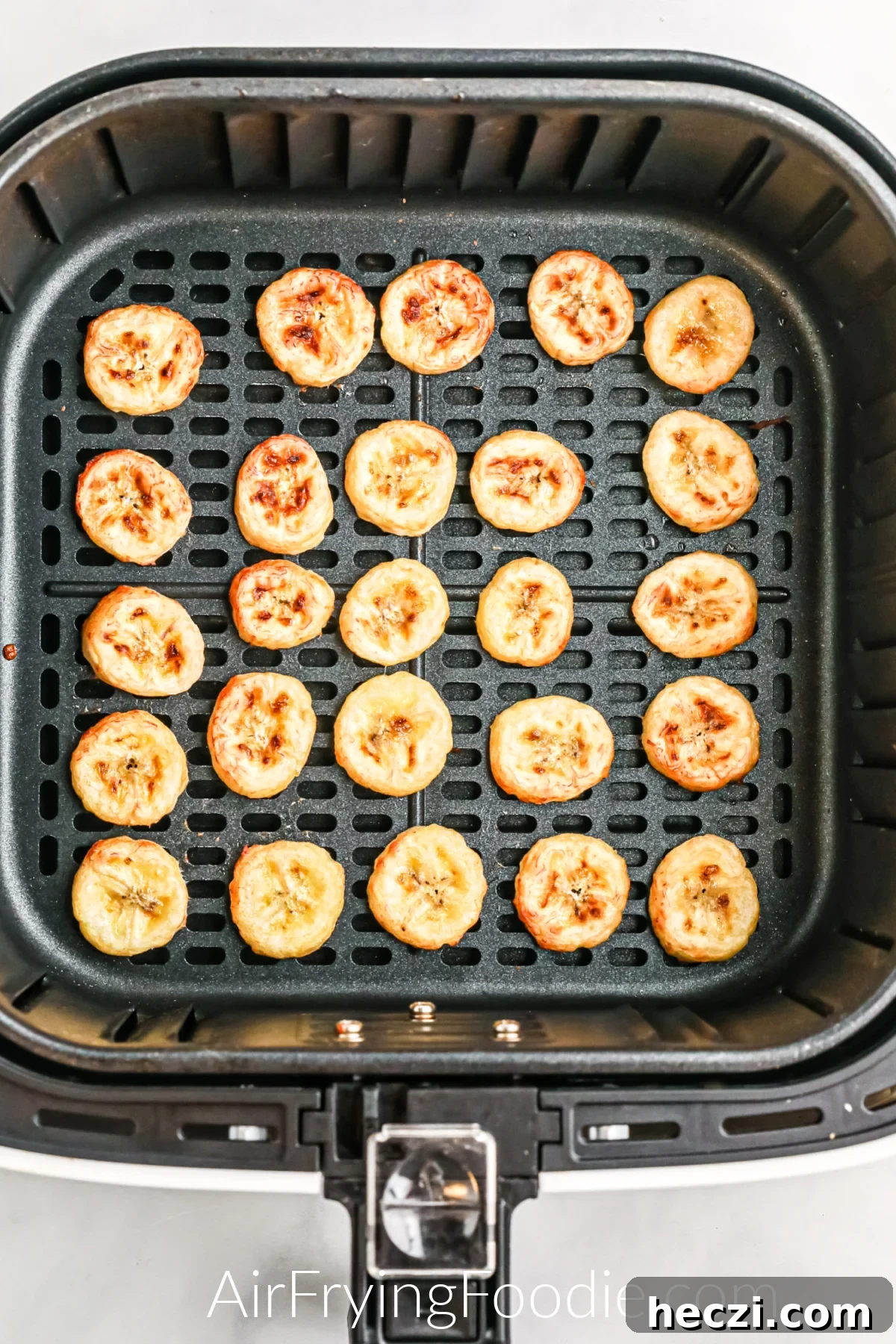 Crispy Air Fryer Banana Chips Recipe — Quick Snack at Home 7 Banana slices in a single layer in the basket of the air fryer.