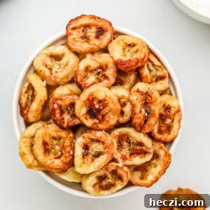 Crispy Air Fryer Banana Chips Recipe — Quick Snack at Home 10 Banana chips made in the air fryer, served in a white bowl with a sprinkling of kosher salt on top.