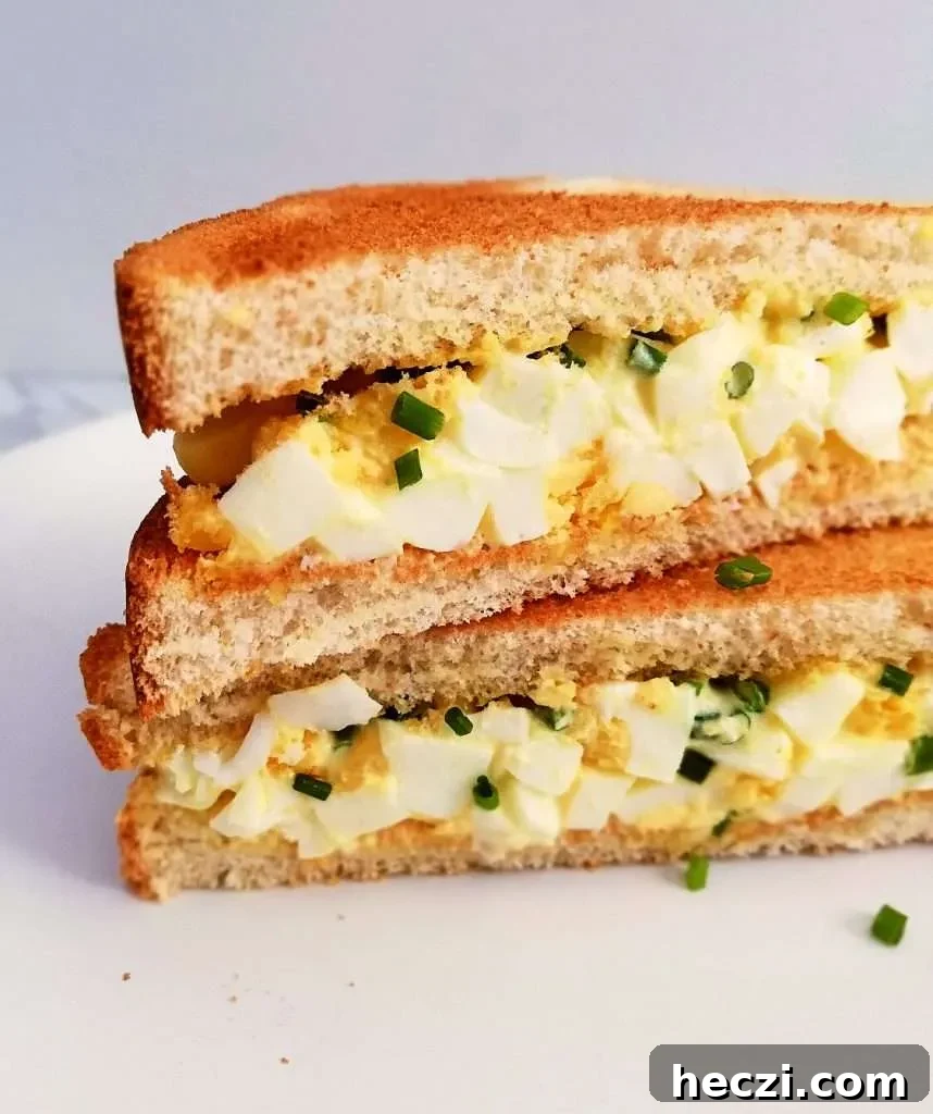 egg salad sandwich sliced in half and stacked close up left