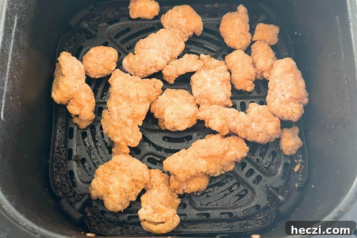 Crispy chicken in air fryer basket. 