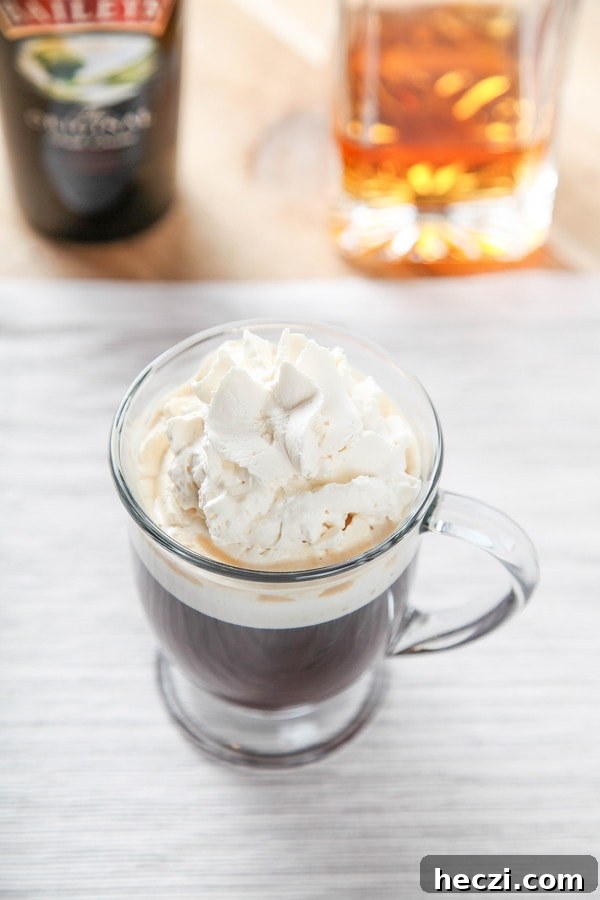 Irish Coffee Recipe in a glass mug with bottles of Jameson and Bailey's in the background. 