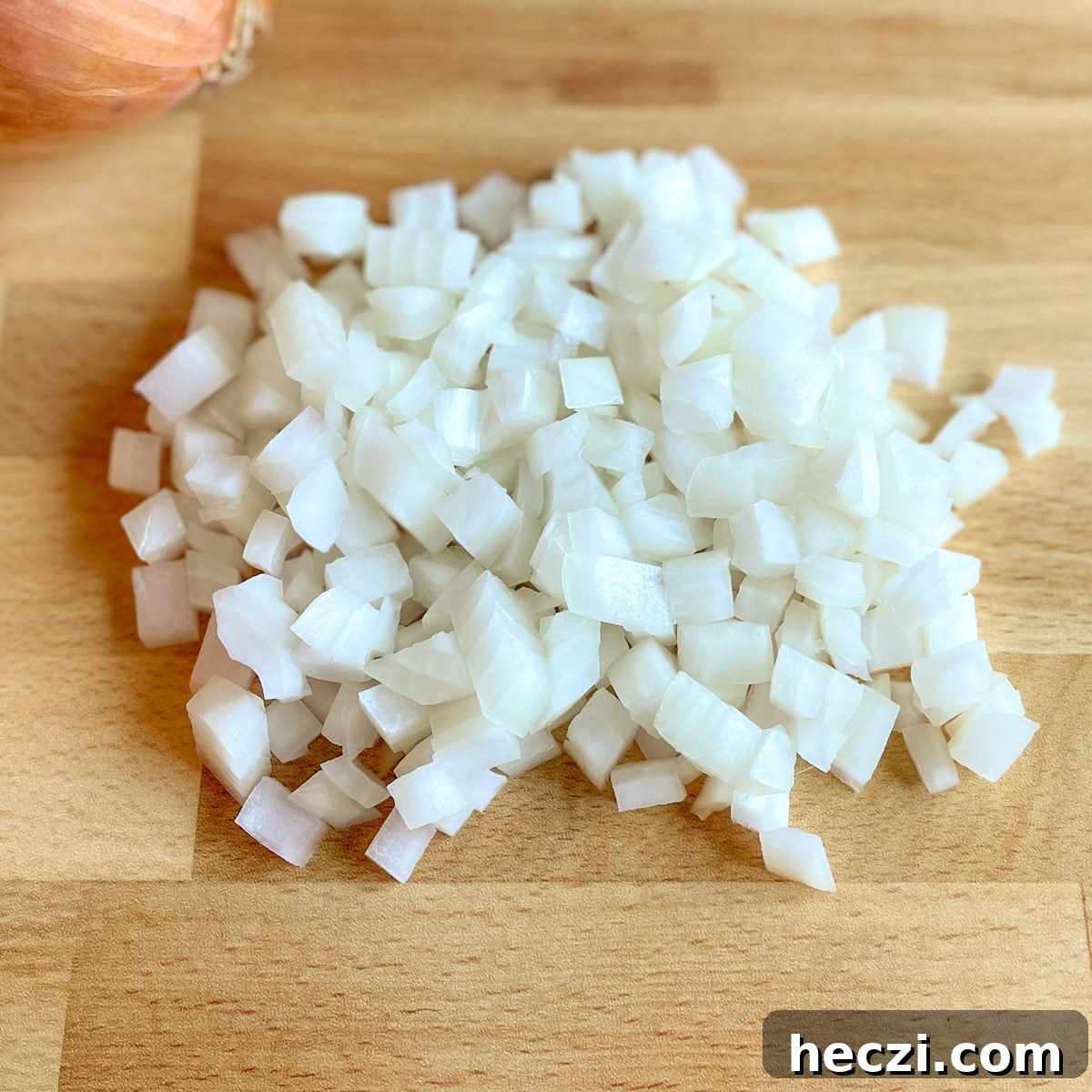 Slow Cooker Lamb Ragu: Tender Rustic Pasta Sauce Recipe 4 Diced yellow onion with a yellow onion in the background on a butcher block cutting board