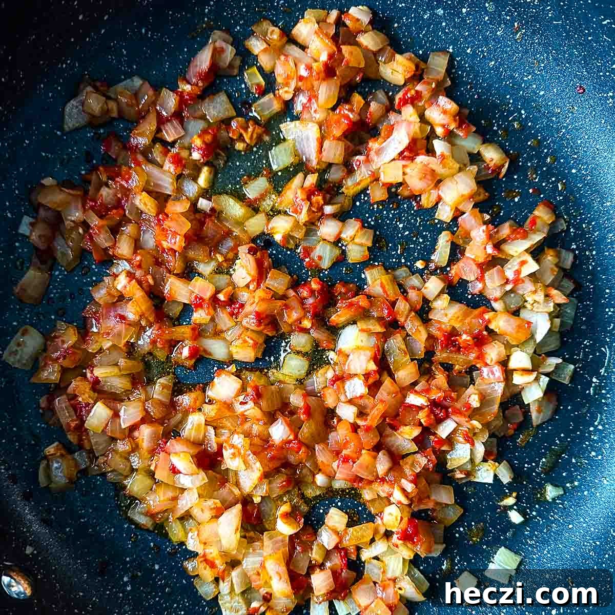 Slow Cooker Lamb Ragu: Tender Rustic Pasta Sauce Recipe 9 cooked down tomato paste in a gray frying pan with sweated onion, garlic, and chili flakes.