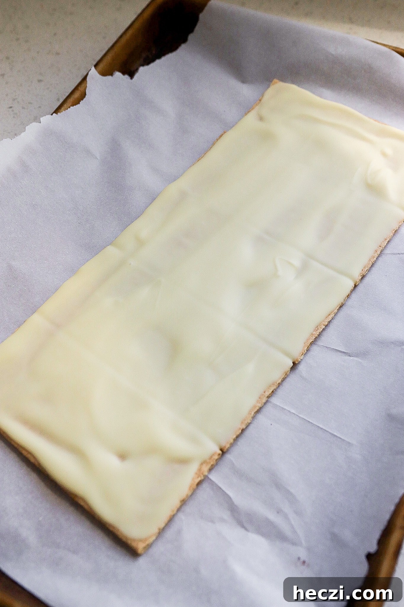 Side view of graham crackers on parchment lined paper with white chocolate on top of them.