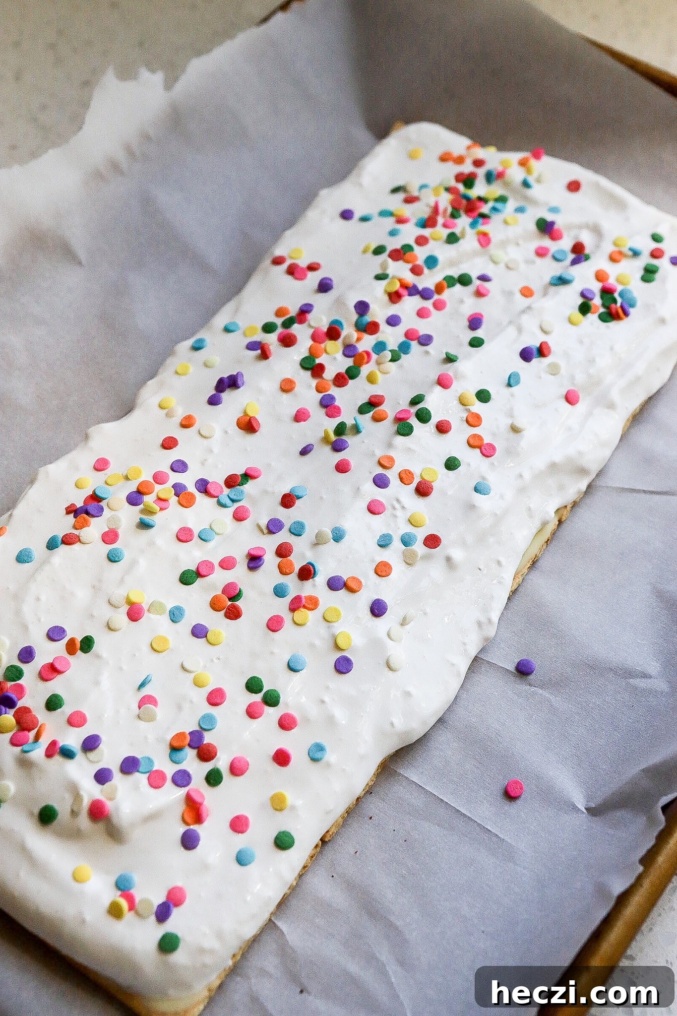 Side view of cool whip mixed with protein powder layered on graham crackers with rainbow sprinkles on top.