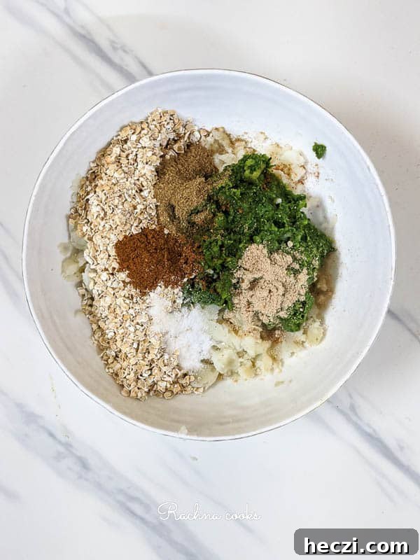Hara Bhara Kabab Recipe — Tawa and Air Fryer Methods 5 Mashed potato, oats, green mix and spices in a white bowl.