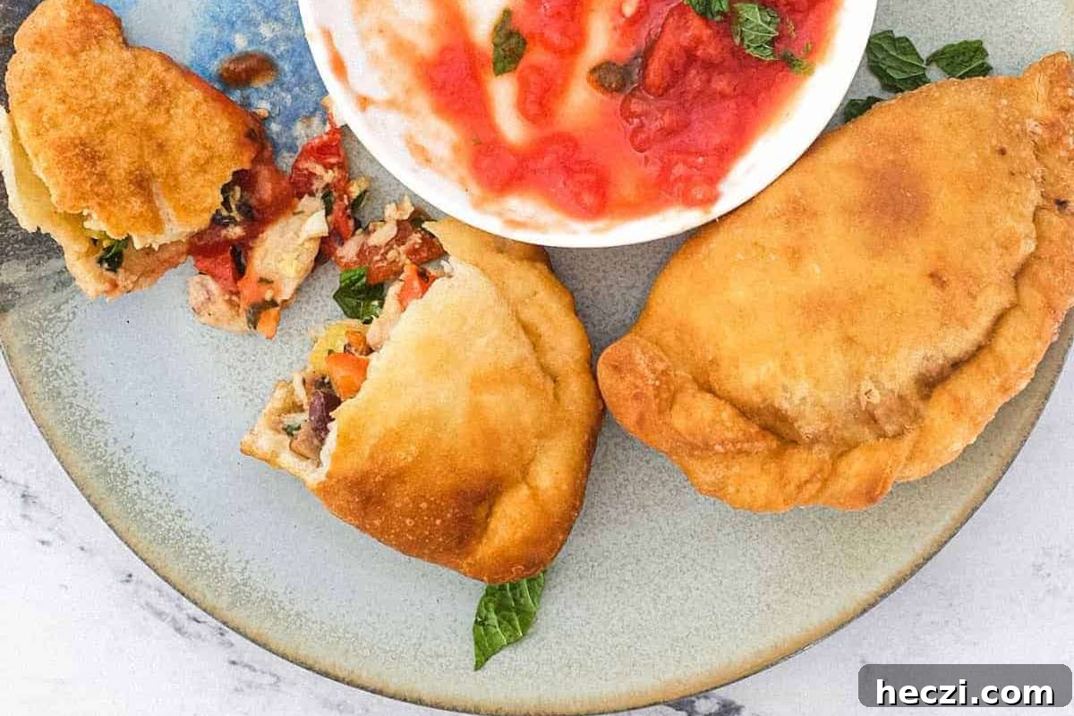 Two Italian empanadas served with dipping sauce, perfect as appetizers.