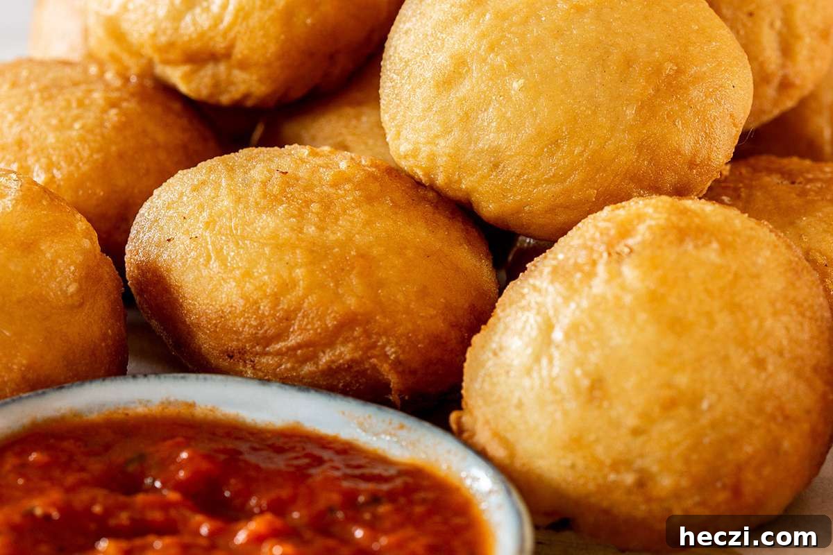 A pile of fried Italian dough balls served as appetizers, accompanied by a delicious dipping sauce.