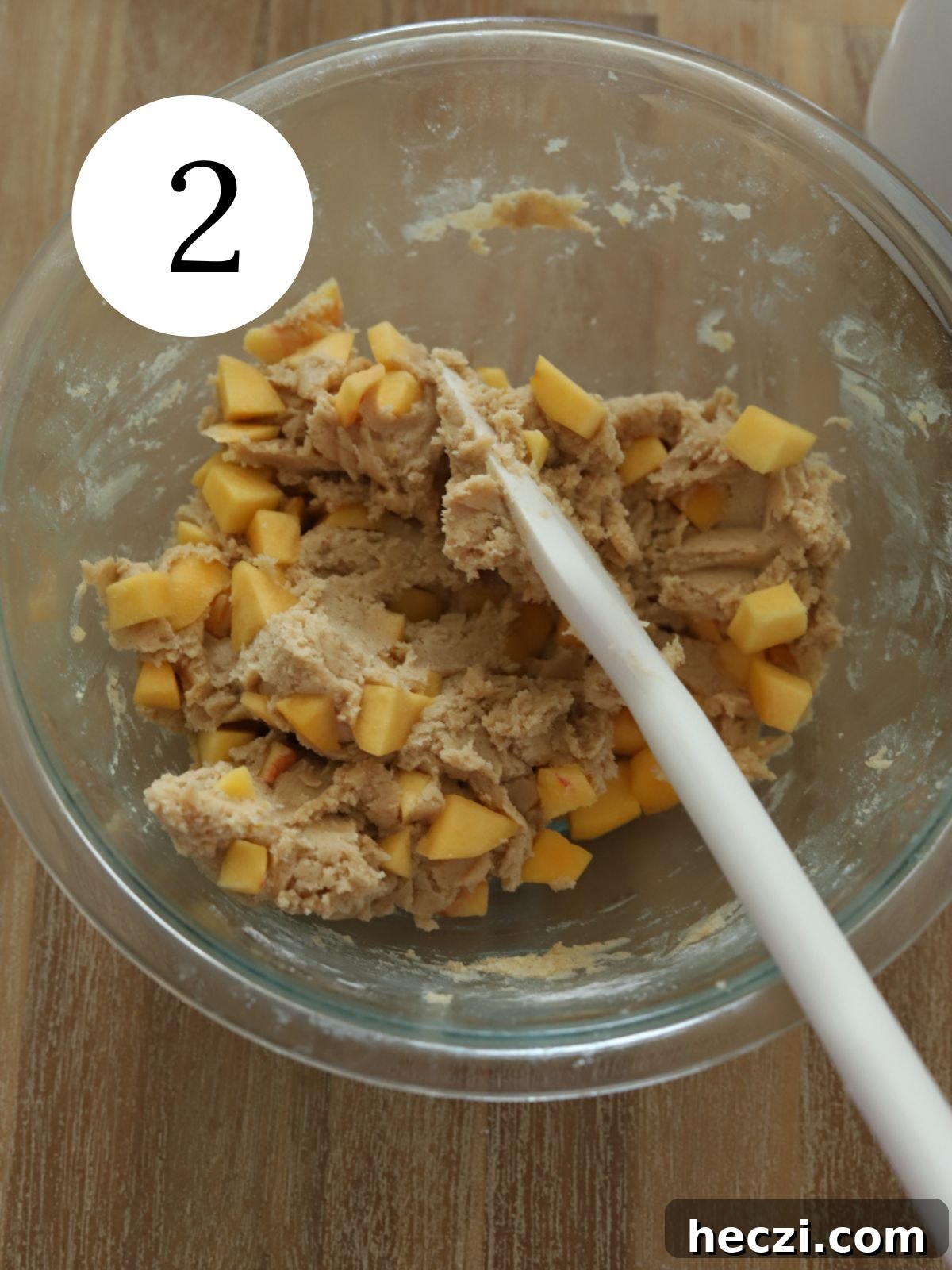 Peach Cobbler Cookies Recipe: Soft Peach Jam-Filled Cookies 5 Chopped peaches stirred into cookie dough with a spatula in a glass bowl.