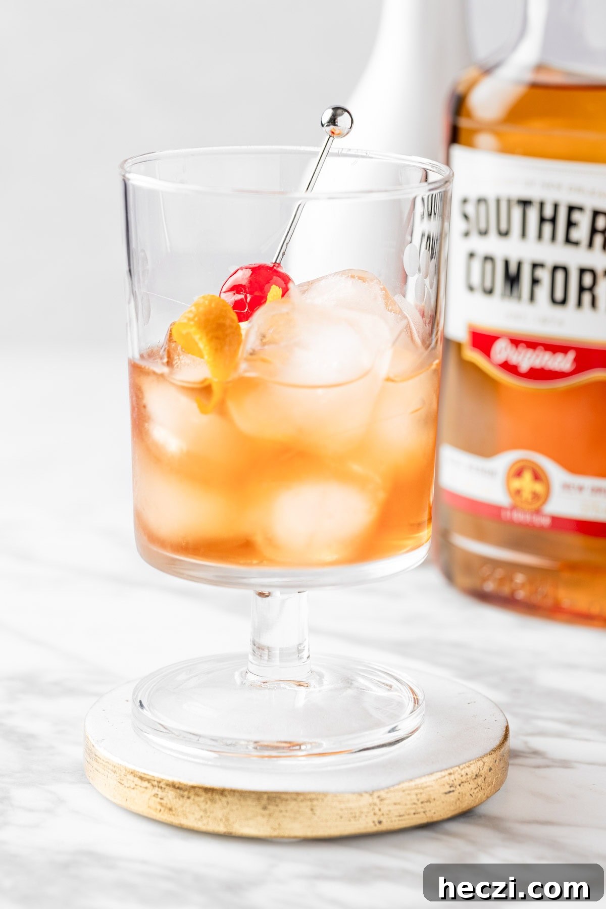 A Southern Comfort Old Fashioned garnished with a maraschino cherry and orange peel twist.