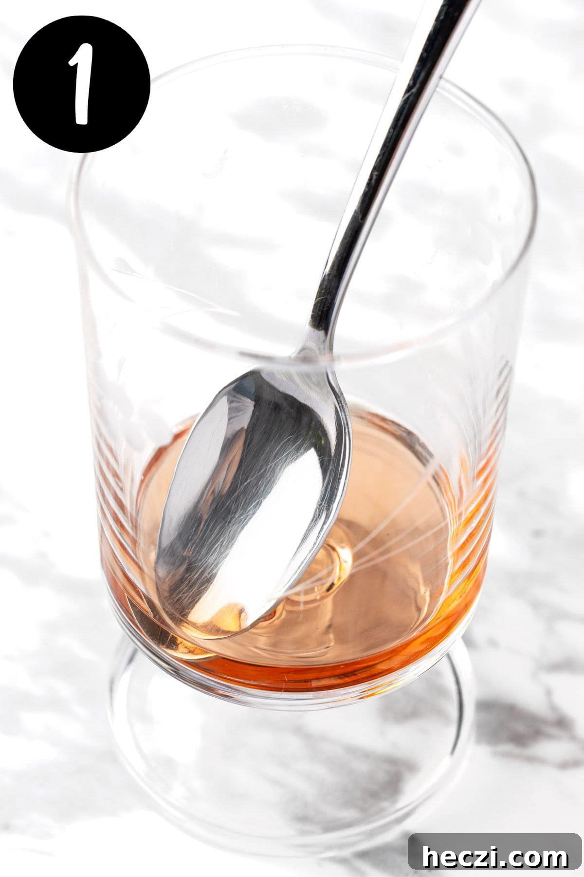 Mixing the simple syrup and bitters together in a cocktail glass.