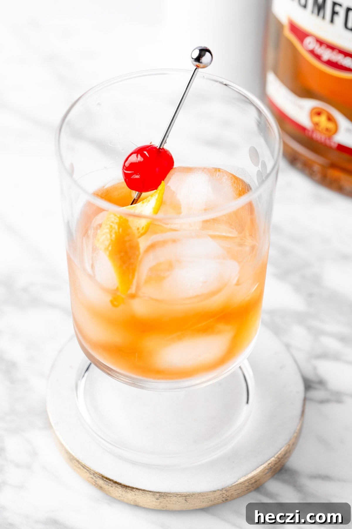 A Southern Comfort Old Fashioned on a round white and gold coaster.