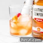 A Southern Comfort Old Fashioned garnished with a cherry and orange peel twist.