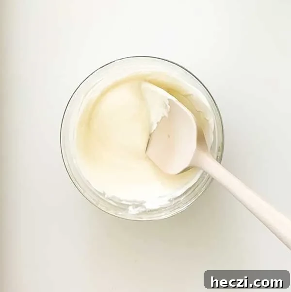 Stirring melted white chocolate in a glass bowl.