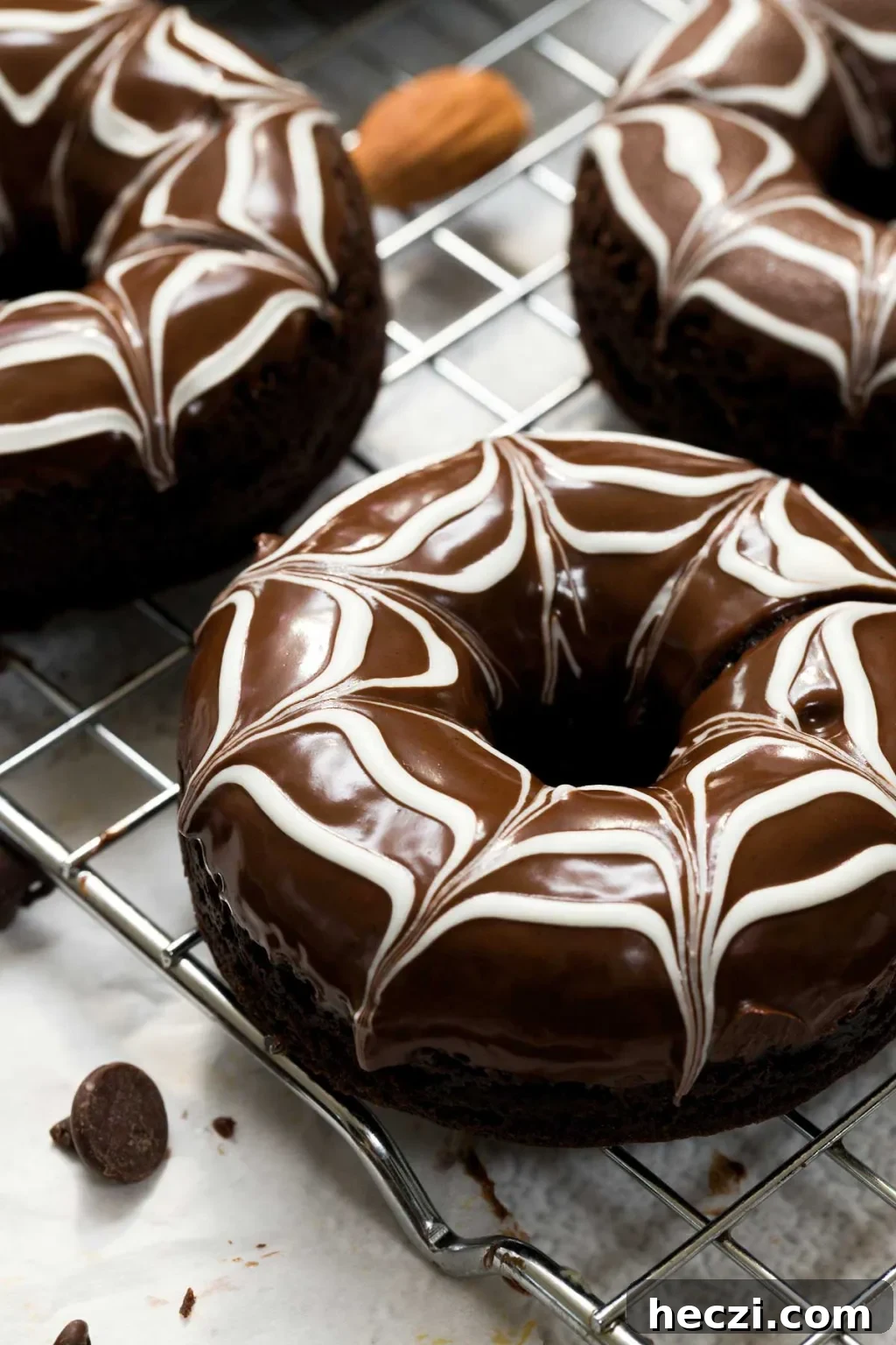 Close-up of a baked chocolate donut with a white chocolate spider web design on top.