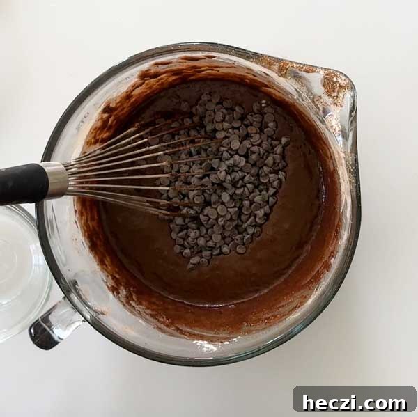 Folding mini chocolate chips into the chocolate donut batter.