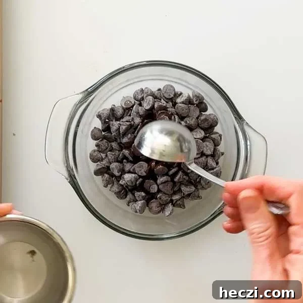 Adding coconut oil to the chocolate chips in a glass bowl.
