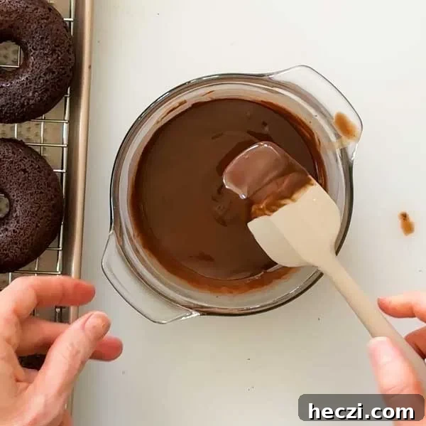 Stirring the melted chocolate in a glass bowl with a spatula.