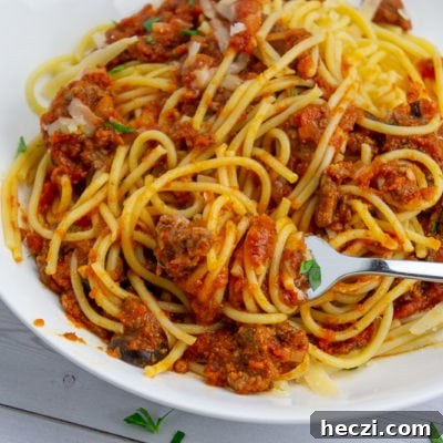 Authentic Homemade Spaghetti Sauce Recipe for Rich, Classic Flavor 8 a white bowl of spaghetti noodles tossed with red sauce on a white wooden table