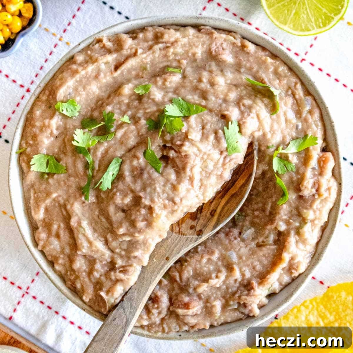 19 Budget-Friendly Bean Recipes to Save You Money Weekly 11 Refried beans with cilantro and a wooden spoon