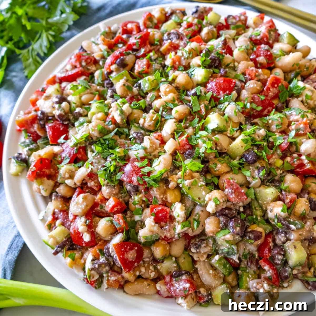 19 Budget-Friendly Bean Recipes to Save You Money Weekly 3 High protein bean salad in a large bowl with lemon wedges and parsley garnish.