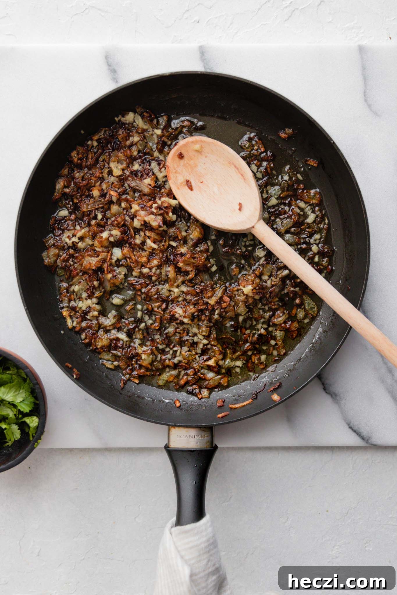 Tadka or browned onions and minced ginger in a medium skillet ready to be mixed in with Sarson Ka Saag