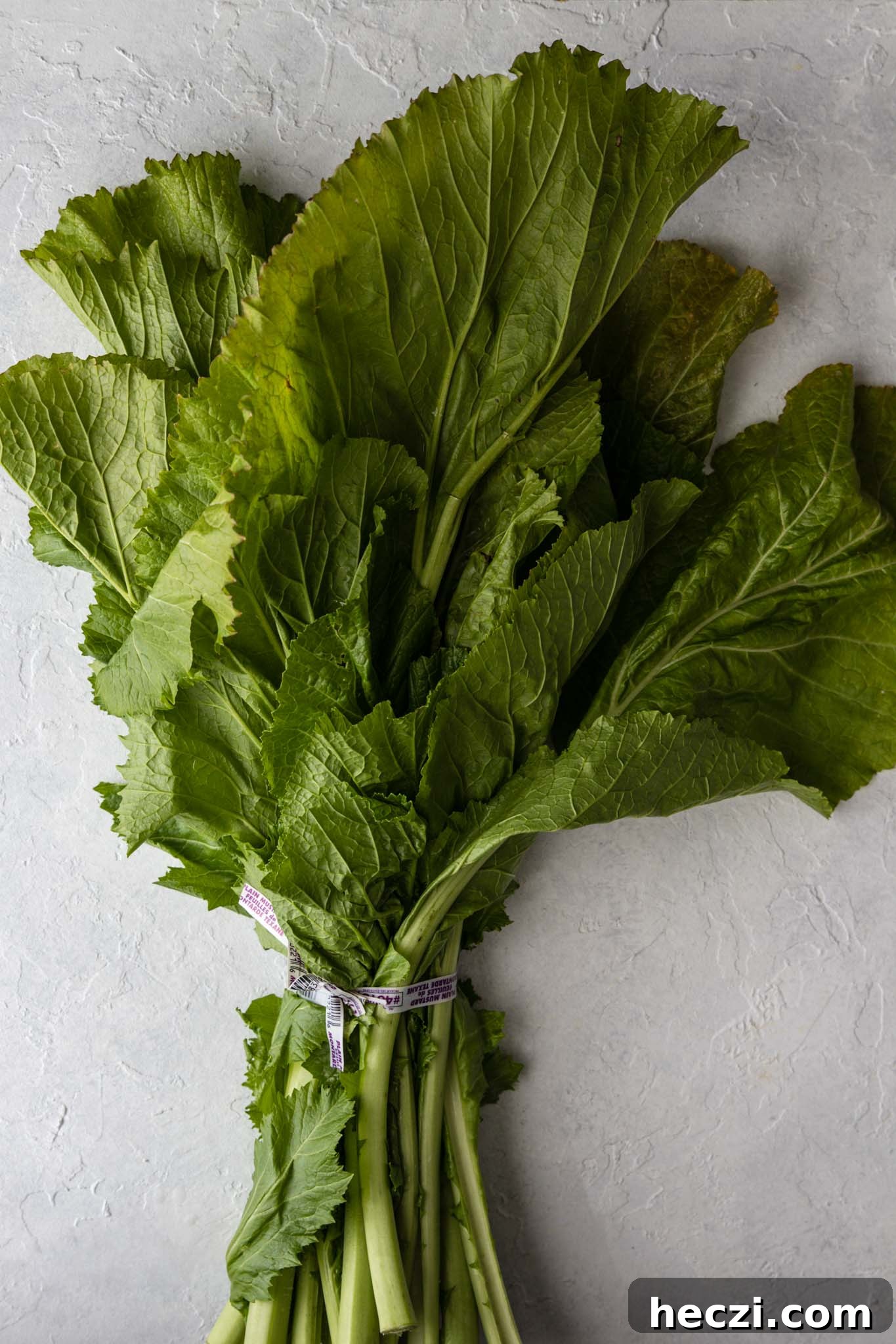 One bunch of Mustard Greens on a white surface