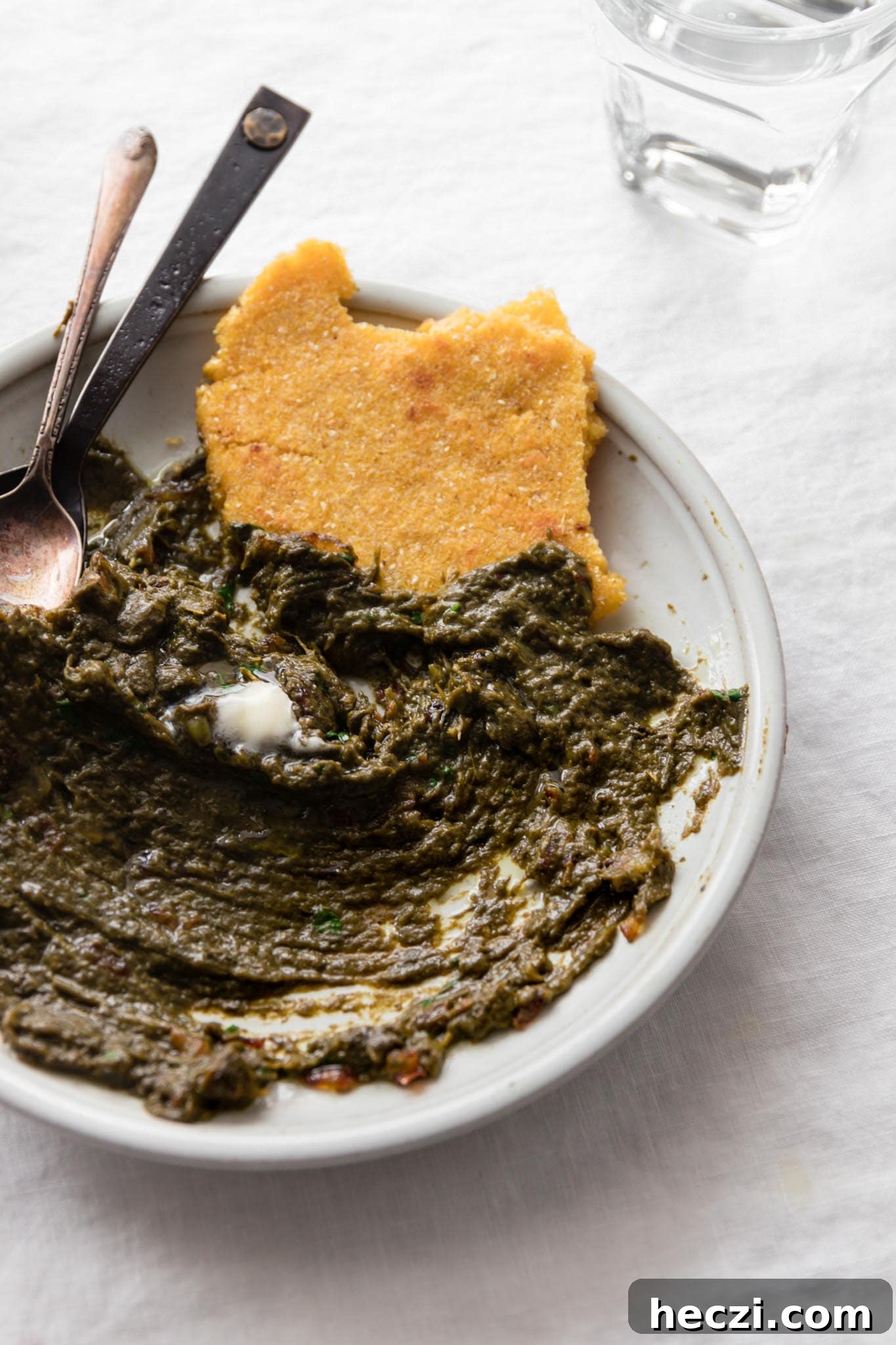 Half eaten plate of Sarson Ka Saag served with Makai ki roti (cornmeal flatbread)