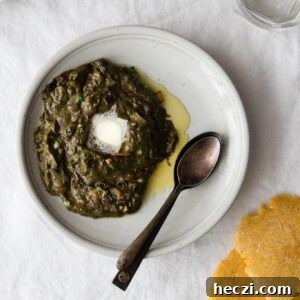 Sarson Ka Saag with a dollop of butter on a plate with spoons and makai ki roti on the side
