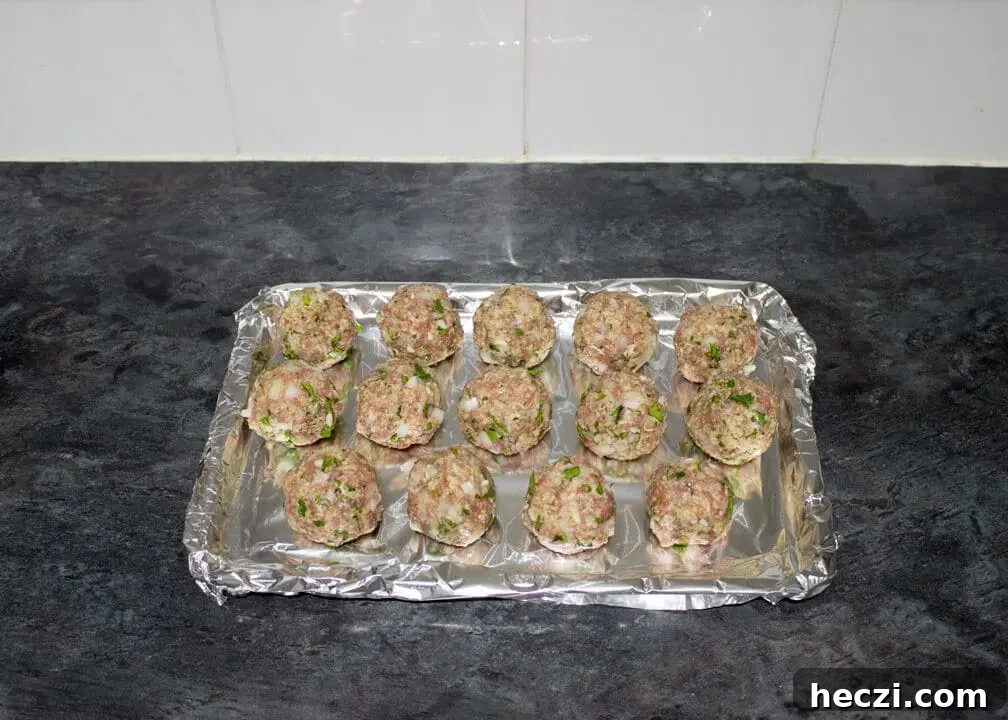 Turkey meatballs rolled into balls on a foil lined baking tray.