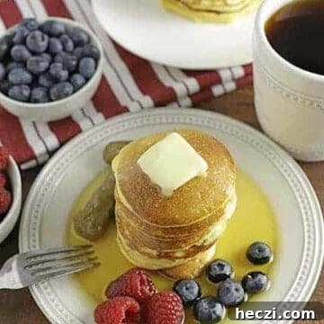 low carb pancakes on white plate with berries on side and syrup on top