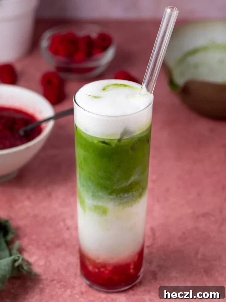 tall glass with iced raspberry matcha latte and a glass straw