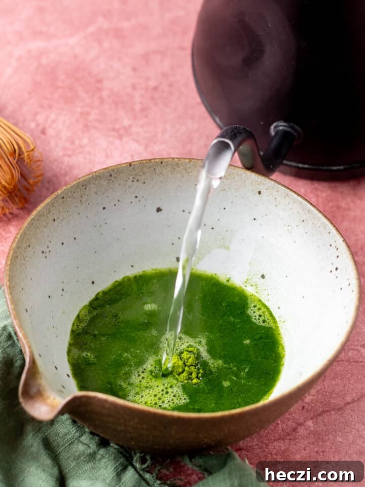 pouring warm water into the matcha green tea
