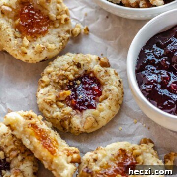 Thumbprint cookies scattered around a bowl of jam.