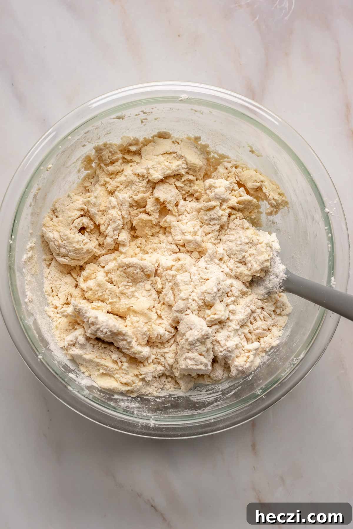 A rubber spatula mixes flour into the sugar cookie dough.