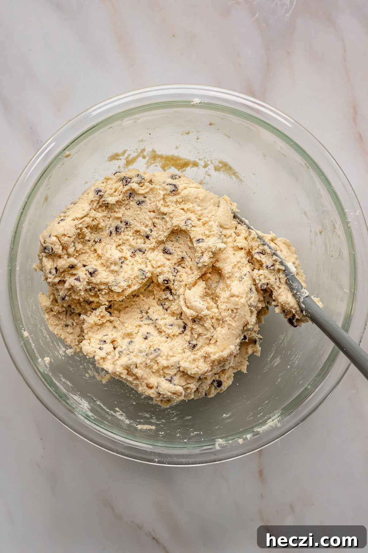 A spatula folds mini chocolate chip into sugar cookie batter.