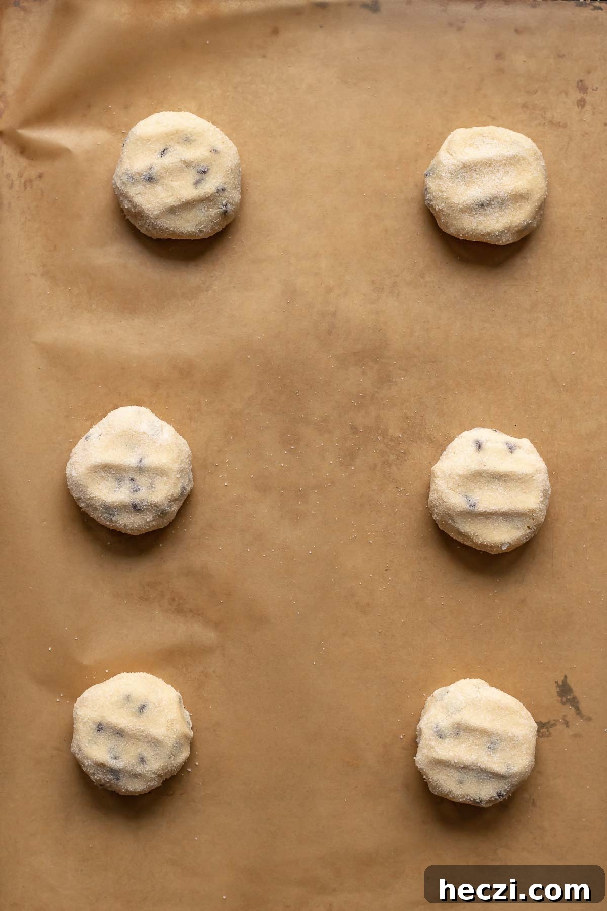 Cookie dough balls on a prepared sheet pan and gently pressed down with finger marks.