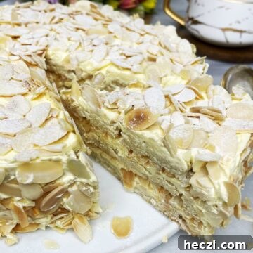 Sliced almond cake covered with flaked almonds on a white platter.