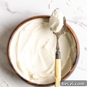 Coconut frosting in a wooden bowl with a spoon of frosting resting on top.