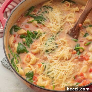 Tortellini white bean tomato soup in pot with spinach and cheese.